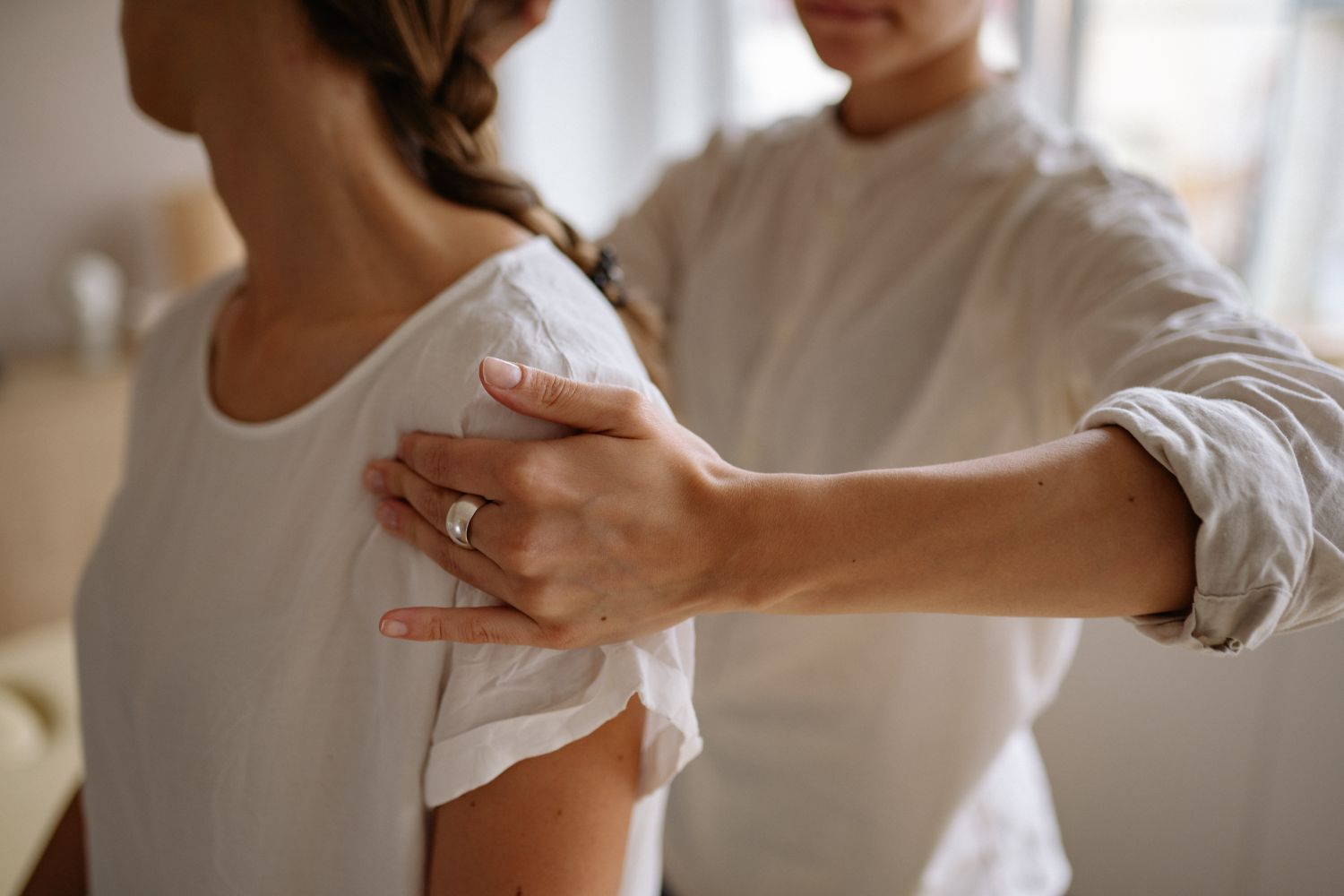 Symbolbild: Hände einer Physiotherapeutin an der Schulter einer Patientin